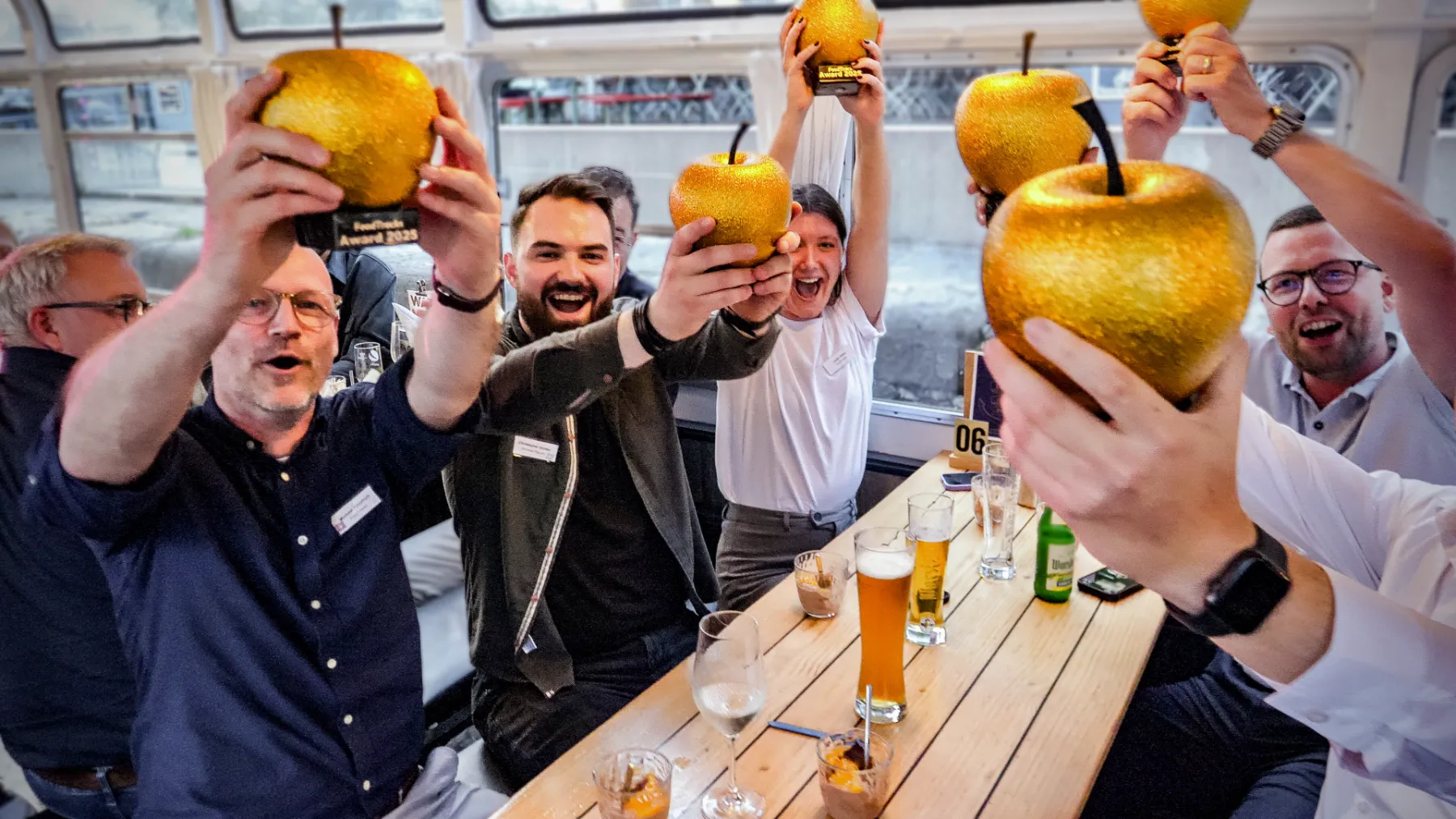 Gäste halten beim FoodTracks Award 2025 goldene Äpfel in die Höhe